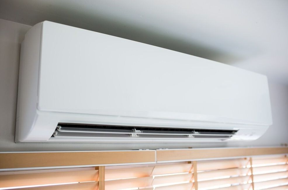 A White Air Conditioner Is Hanging From The Ceiling Next To A Window — Ramm Air Conditioning In Port Macquarie, NSW