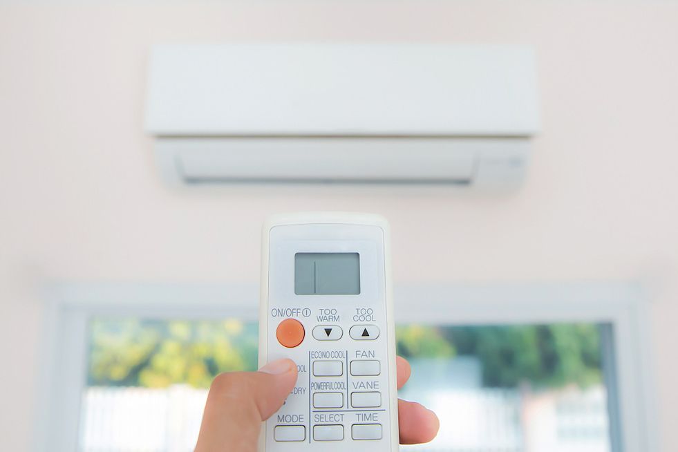 A Person Is Holding A Remote Control In Front Of An Air Conditioner — Ramm Air Conditioning In Port Macquarie, NSW