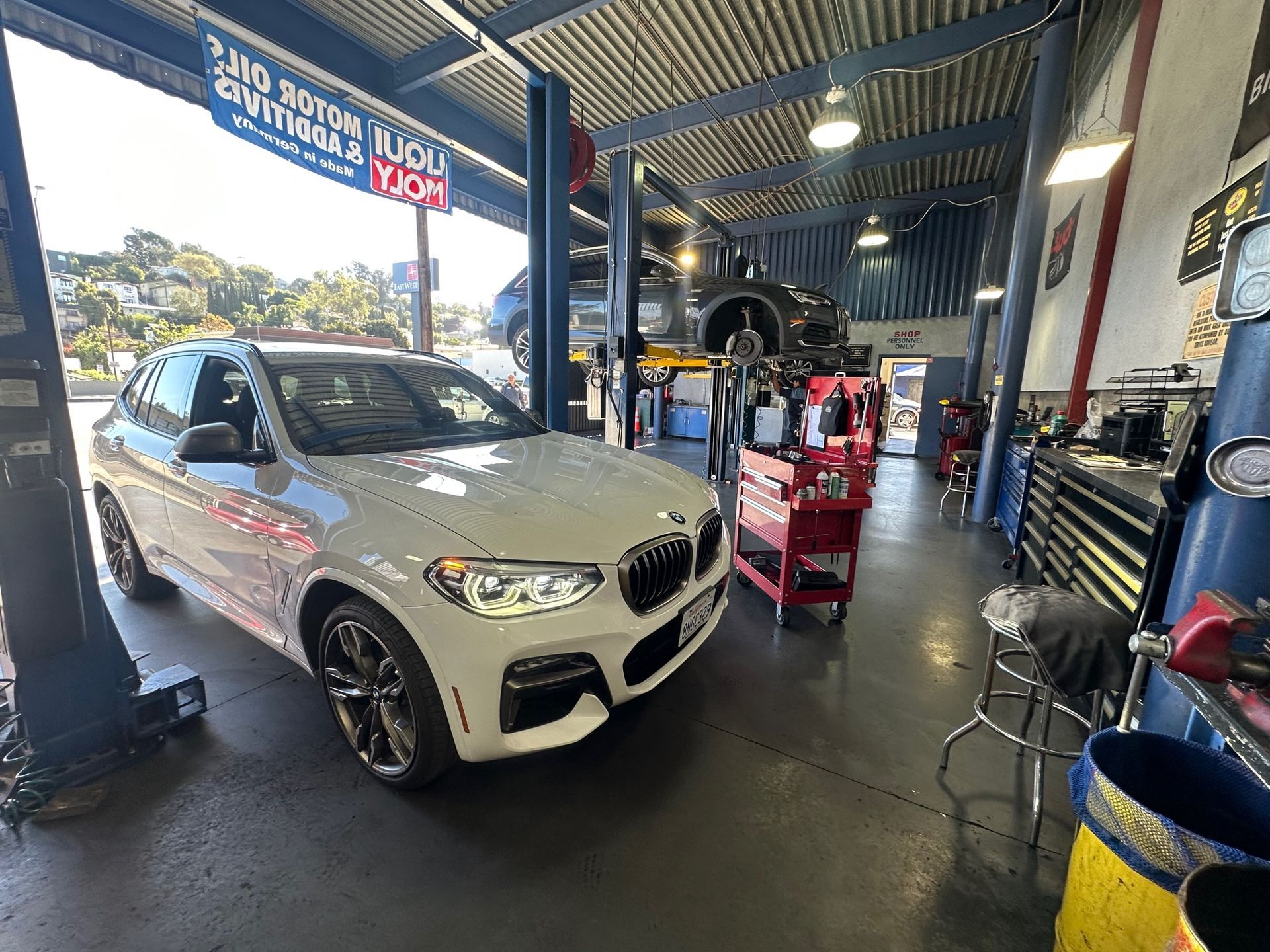 A man is driving a car and pointing at the radio.