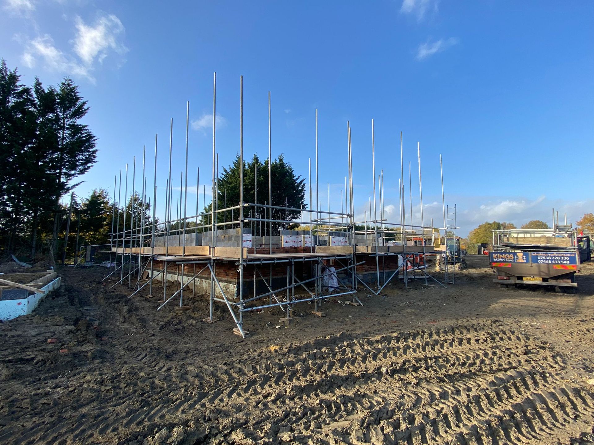 A construction site with scaffolding and a truck in the background.