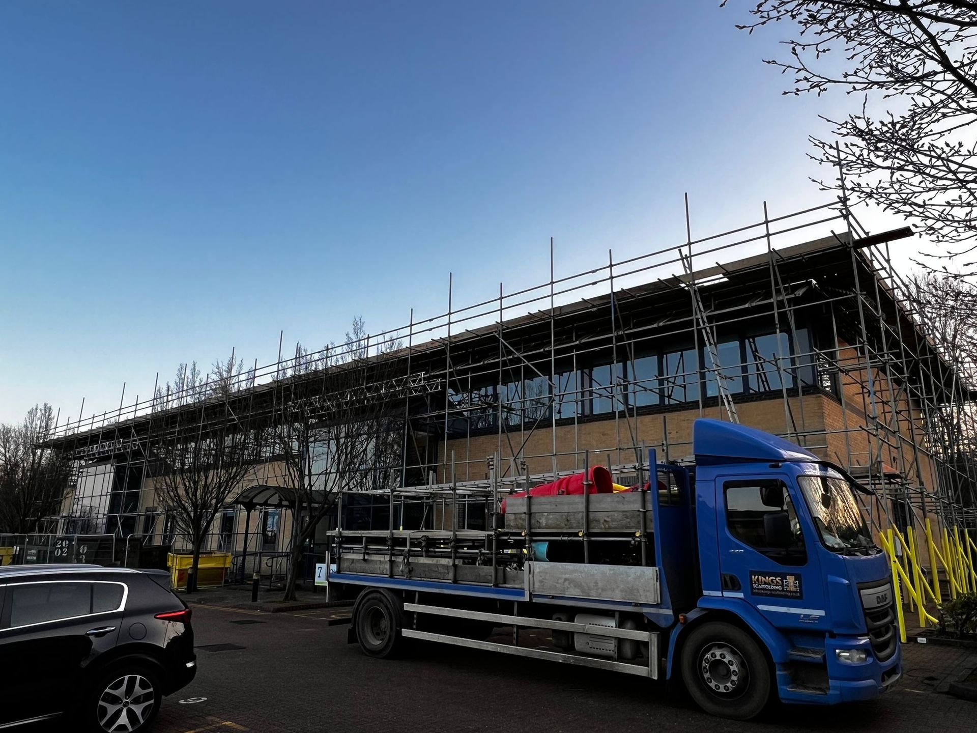 A blue truck is parked in front of a building under construction.