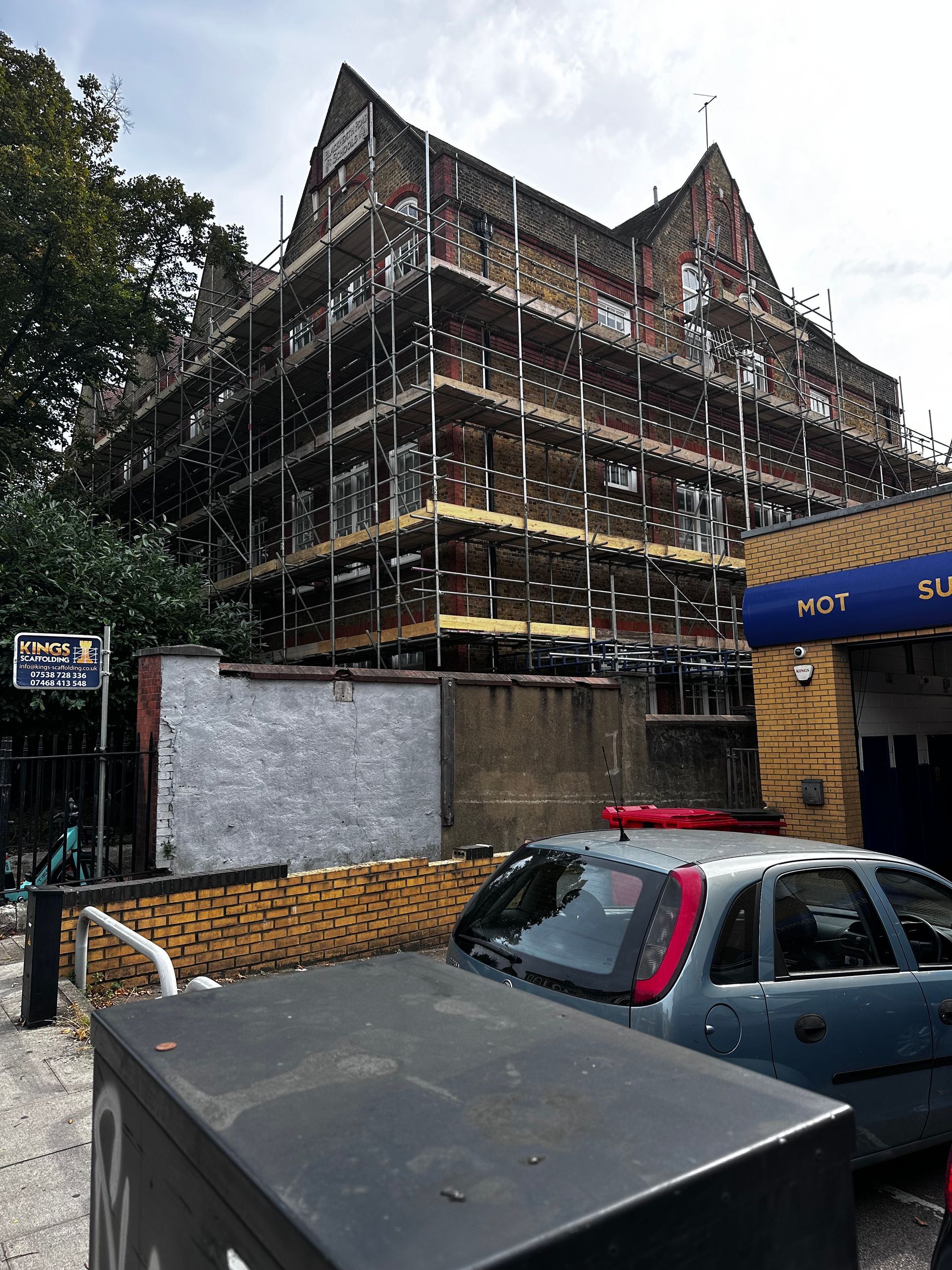 A car is parked in front of a building under construction