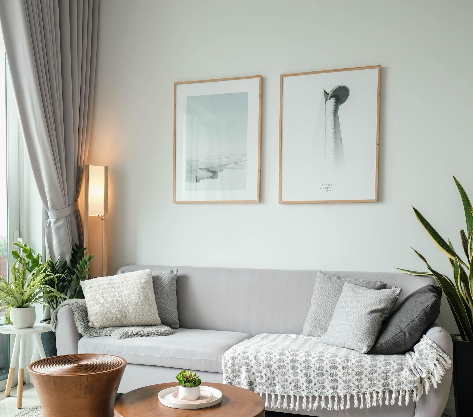 A living room with a couch , table , and two pictures on the wall.