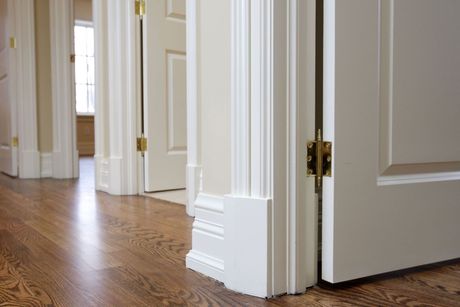 Open white interior doorway with hardwood floor and hallway visible beyond