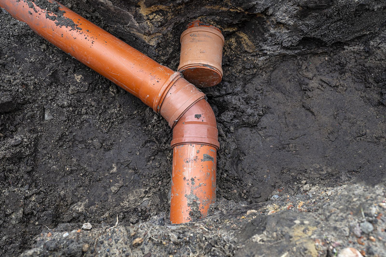 Two pipes are connected to each other in the dirt.