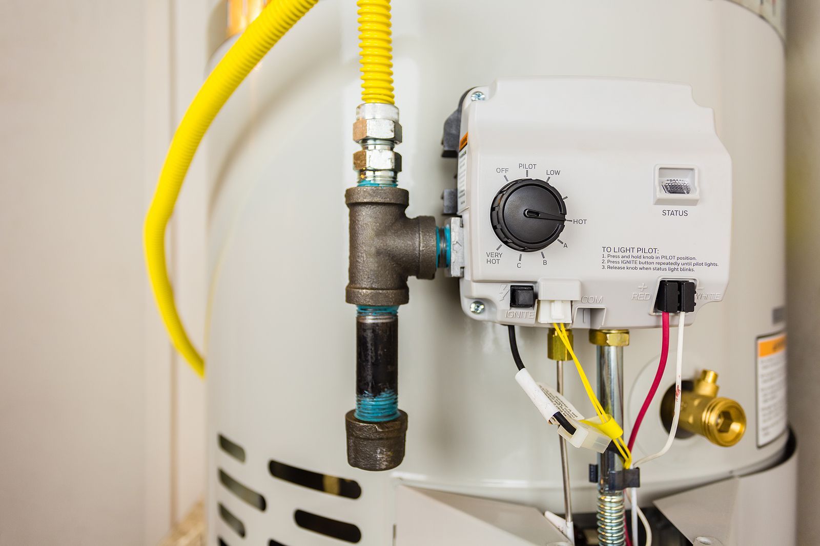 A close up of a gas water heater with a yellow hose attached to it.