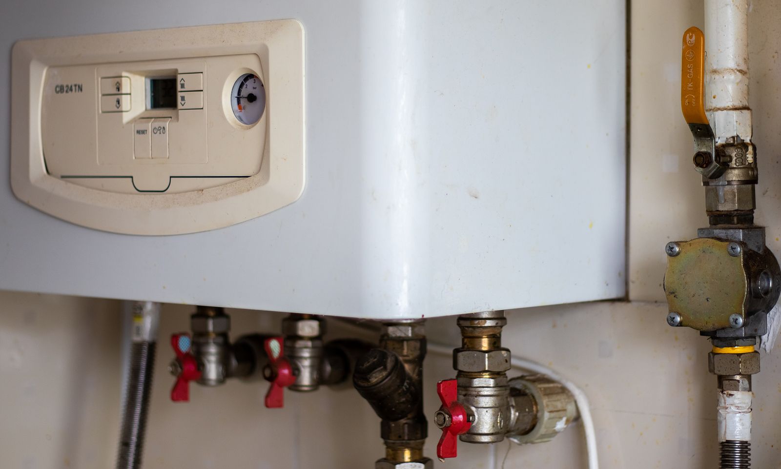 A close up of a water heater with pipes attached to it.