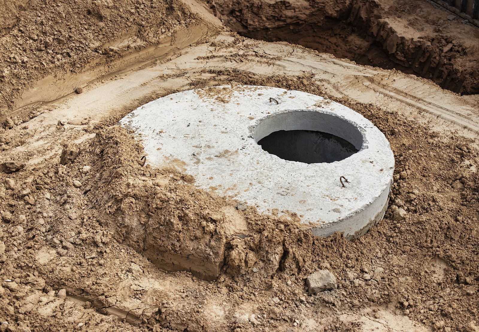 A concrete ring with a hole in the middle is sitting in the dirt.