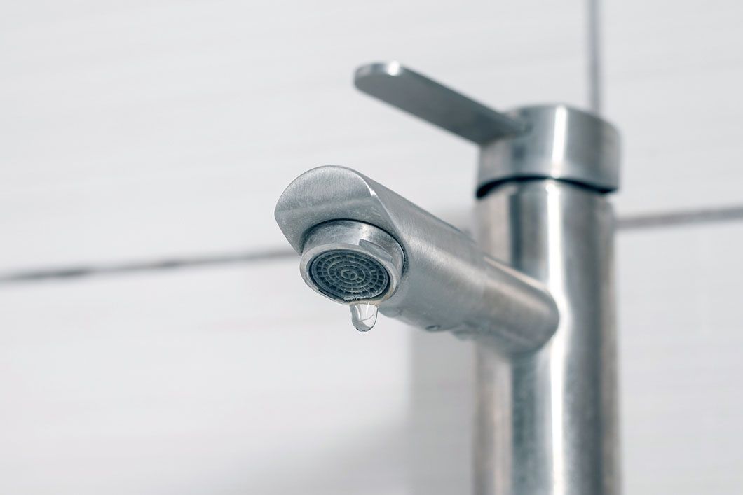 A close up of a faucet with water dripping from it.