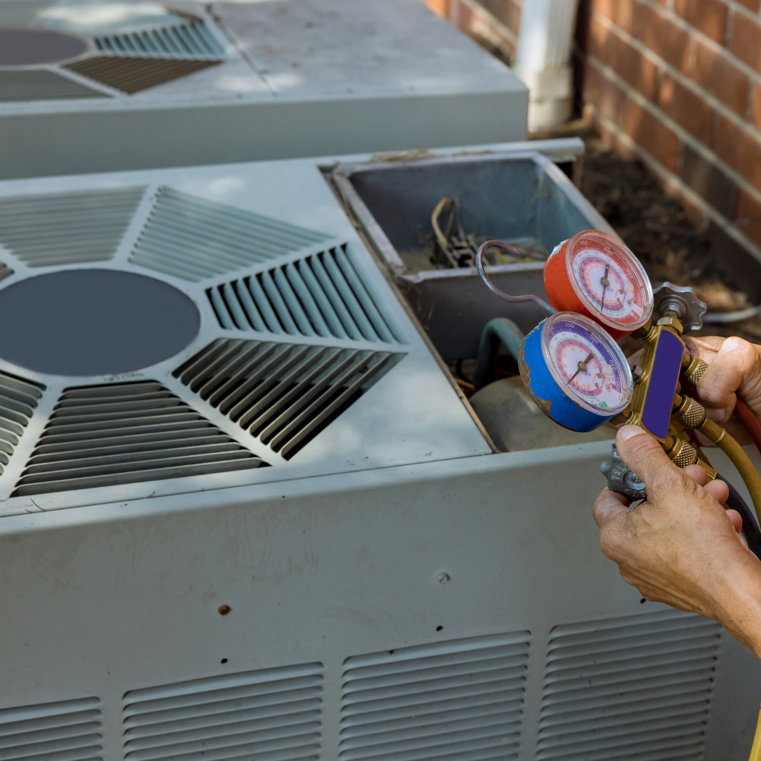 A person is working on an air conditioner with two gauges on it