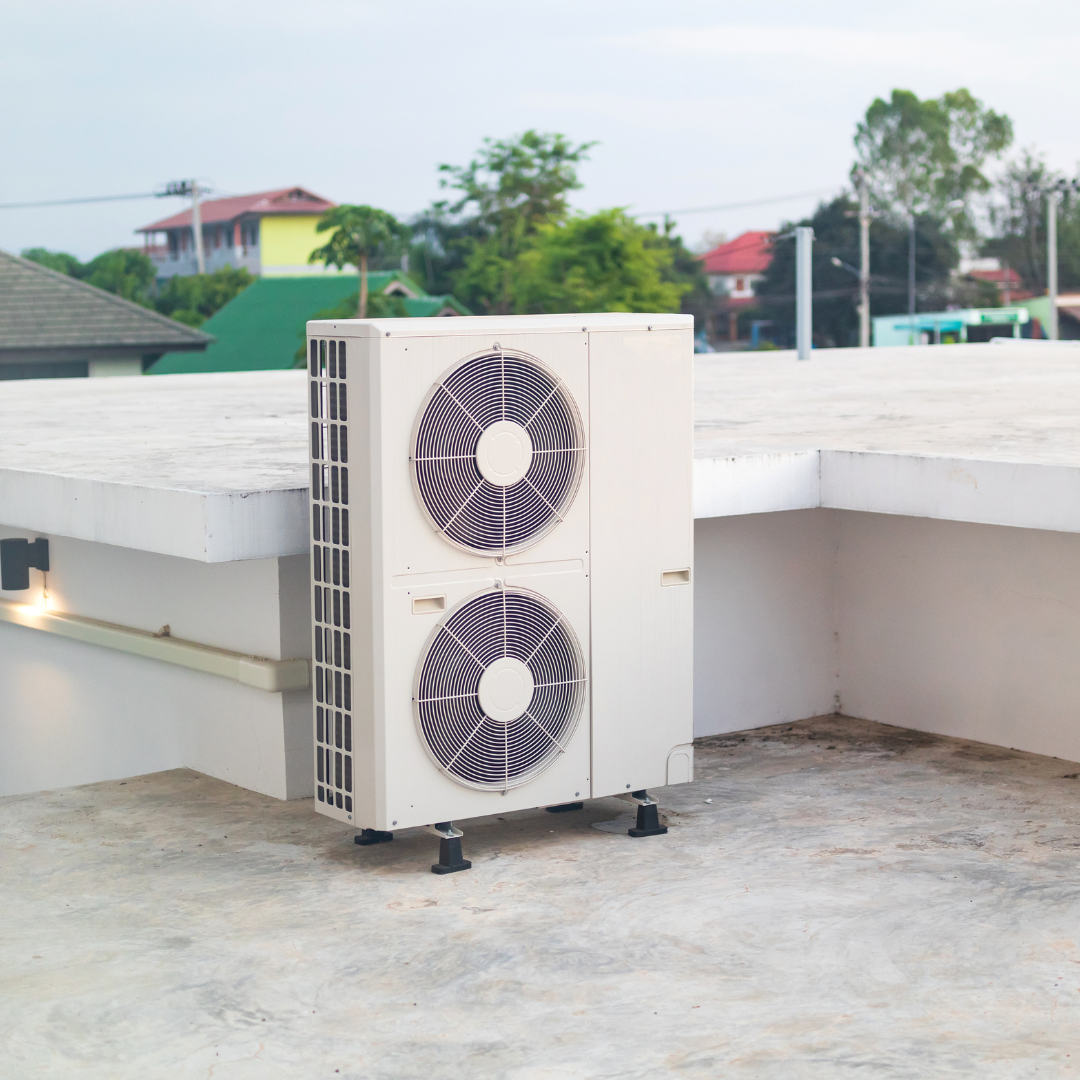 A white air conditioner is sitting on top of a concrete roof.