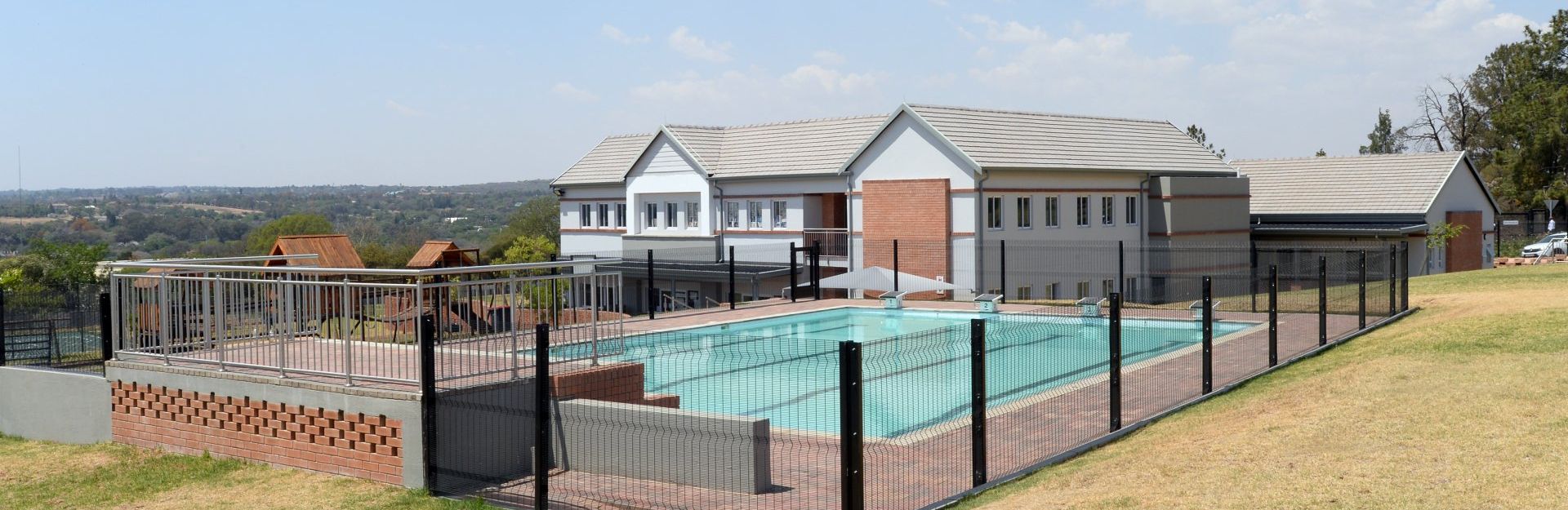 A large house with a swimming pool behind a fence