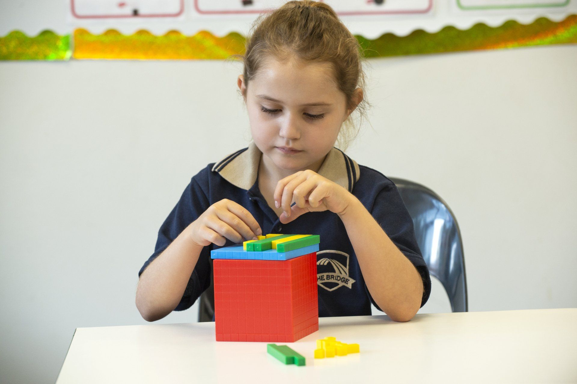 a young girl is sitting at a table playing with blocks .
