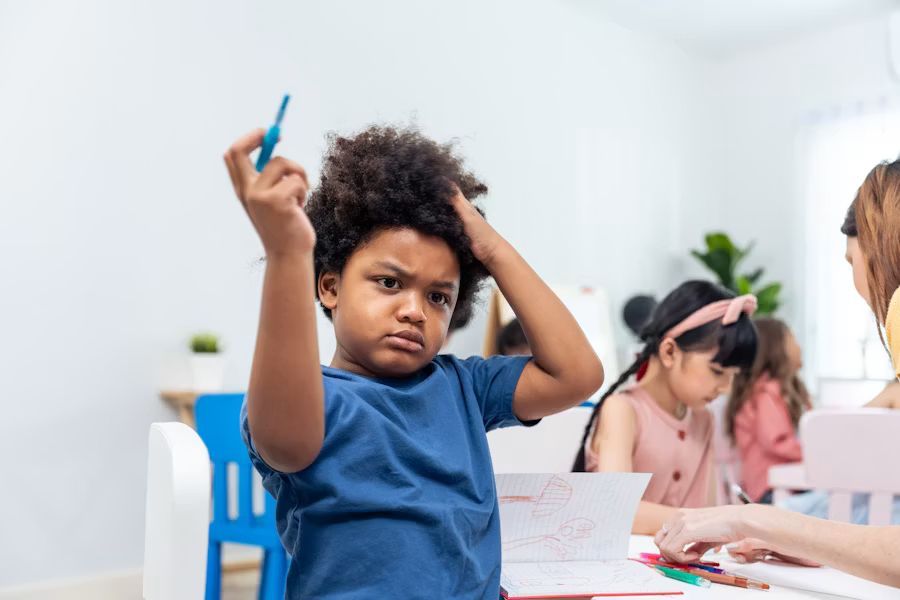 A boy in a blue  shirt is holding a pen