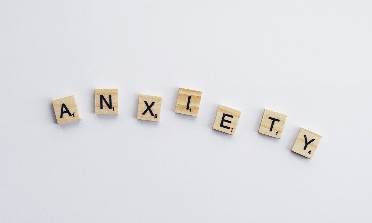 The word anxiety is written in scrabble tiles on a white surface.