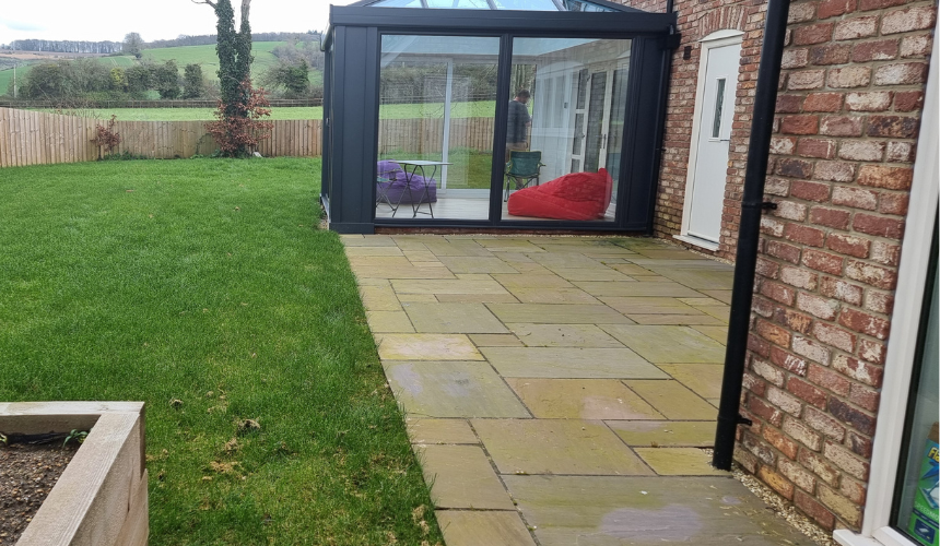 A plain back garden with standard turf and a simple patio. 