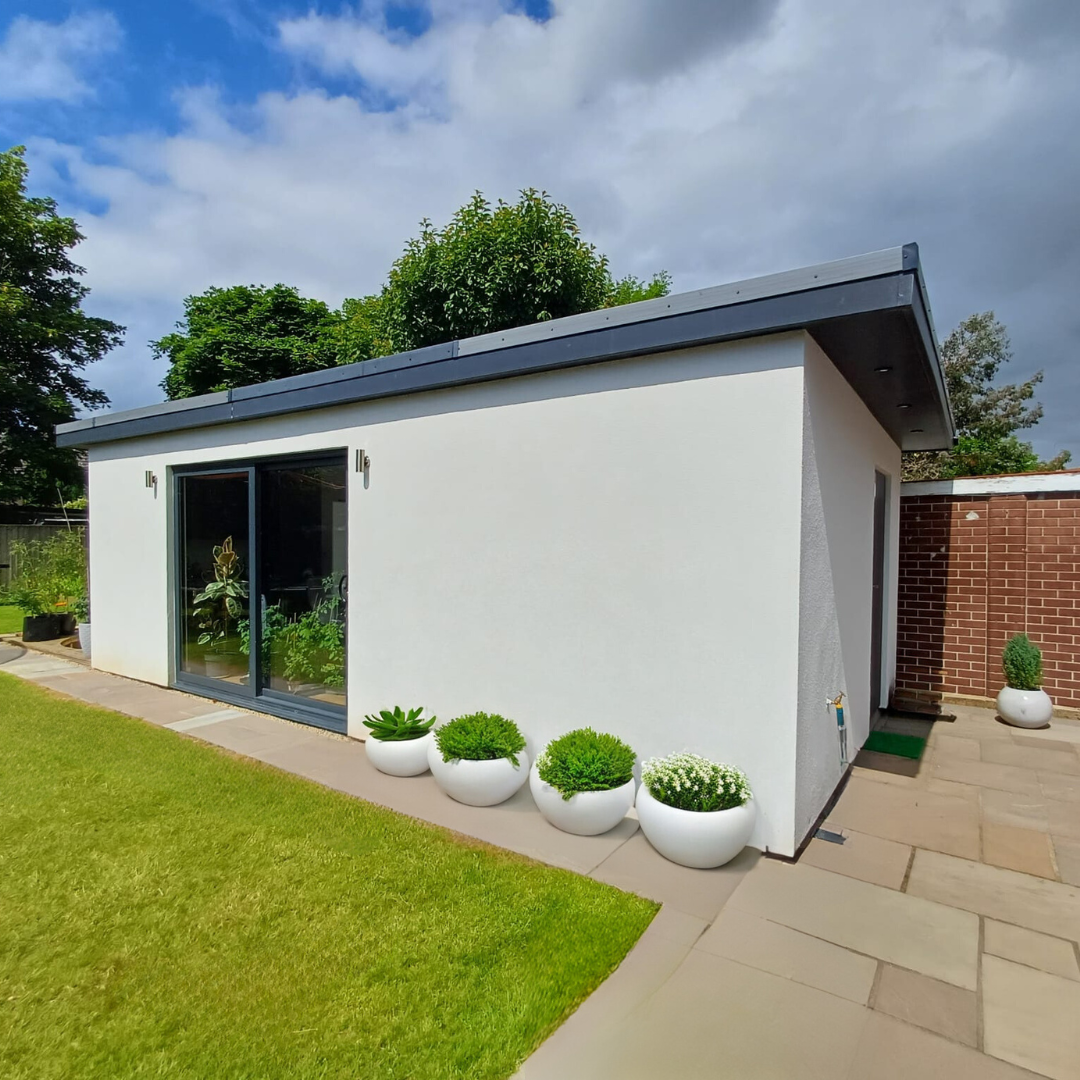 A sleek modern garden cabin with white plastered walls, Alwitra waterproof roofing, and sliding triple-glazed doors by Greenway.
