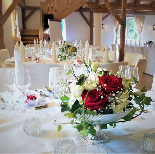 Eine Vase mit roten Rosen und weißen Blumen sitzt auf einem Tisch