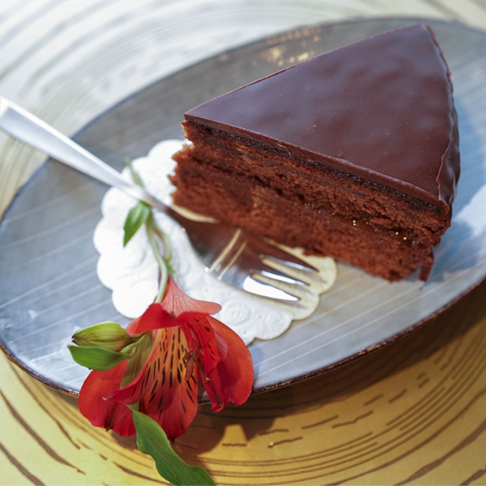ein Stück Schokoladenkuchen auf einem Teller mit einer Gabel und einer Blume