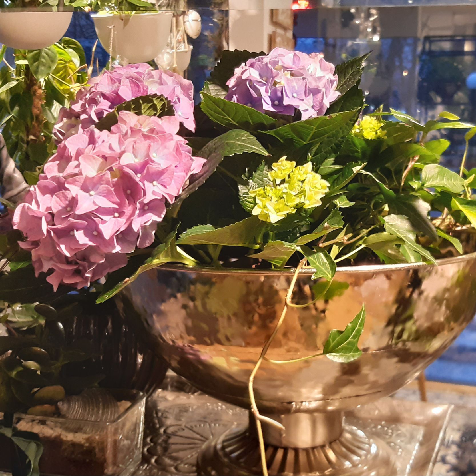 eine Vase mit lila und gelben Blumen und grünen Blättern