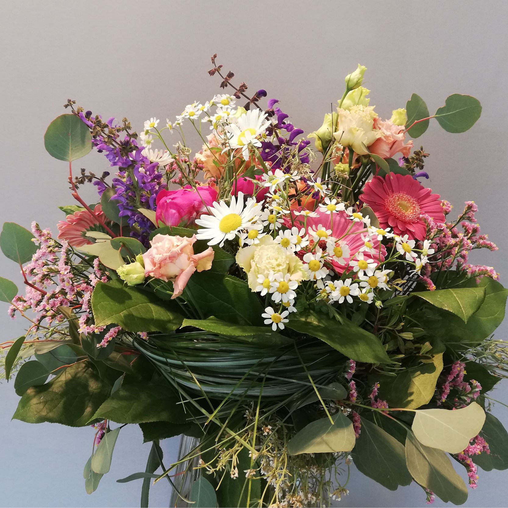 ein Blumenstrauß mit rosa und lila Blumen und grünen Blättern