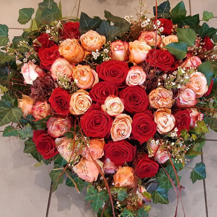 ein herzförmiger Blumenstrauß aus roten und orangefarbenen Rosen