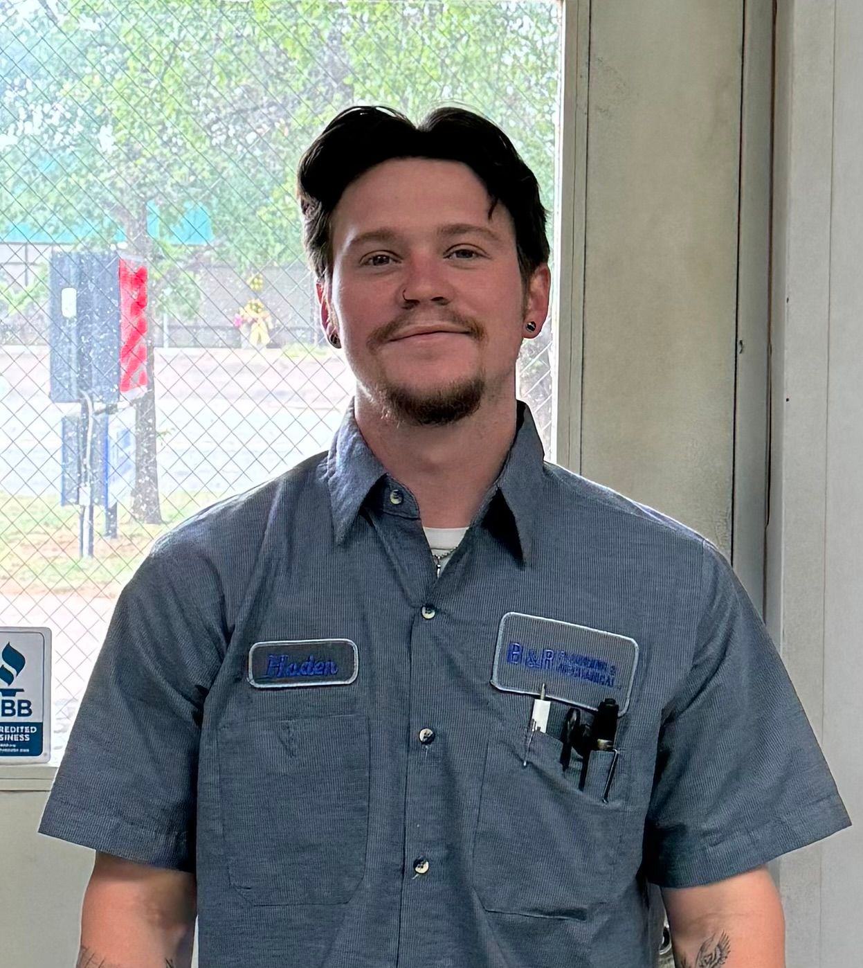 A man wearing a blue striped shirt with a name tag on his chest