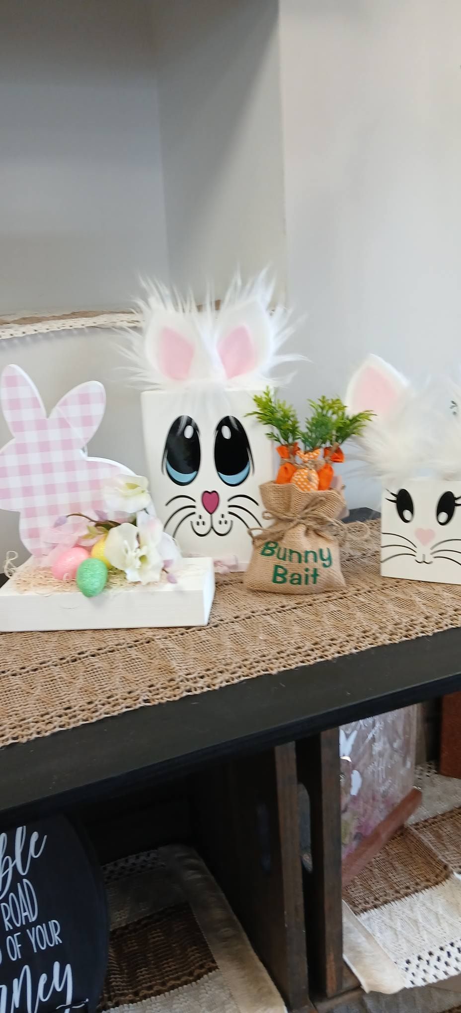 Easter bunny and chick decorations on a shelf with pastel eggs and a pink bunny cutout