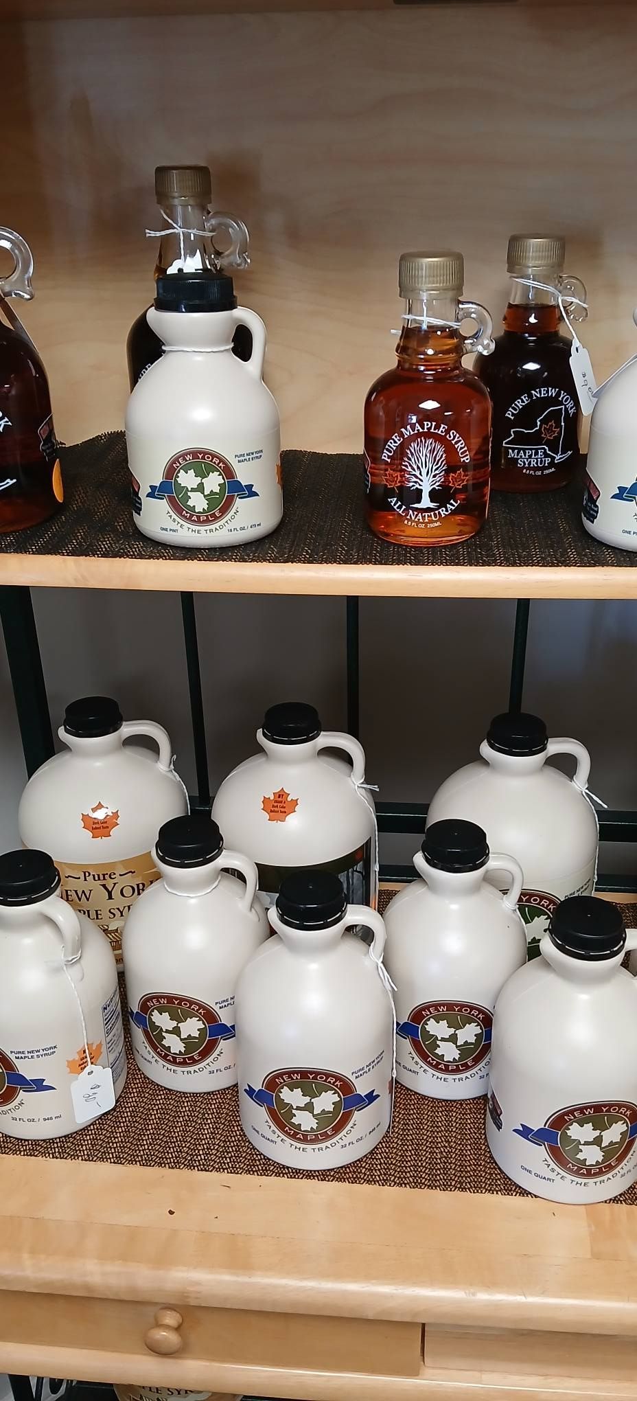 Shelved glass and ceramic liquor bottles, including white bottles with floral labels and brown amber bottles