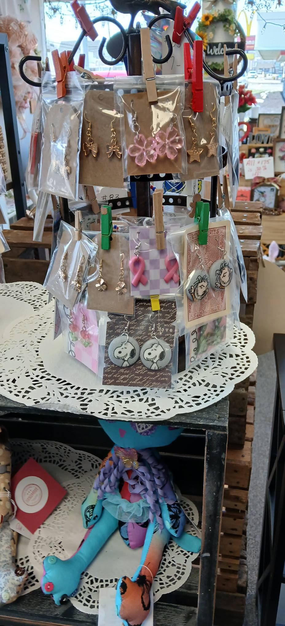 Tiered display of colorful handmade jewelry and accessories on a round white stand in a shop.
