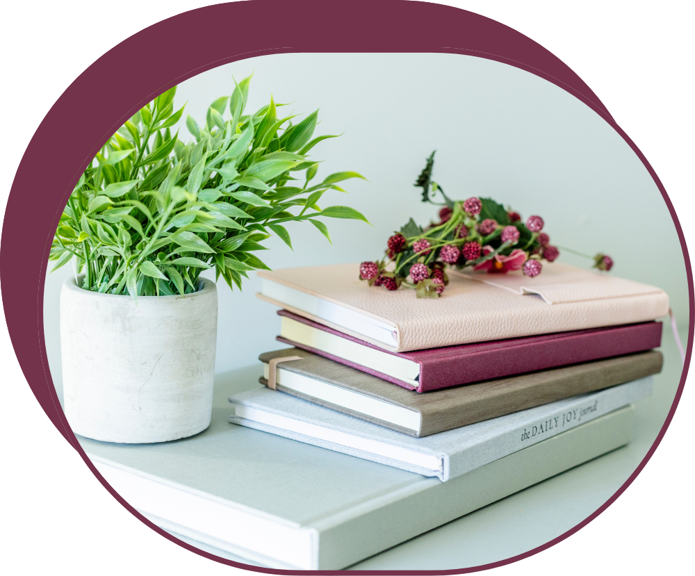 A stack of books and a potted plant on a table.