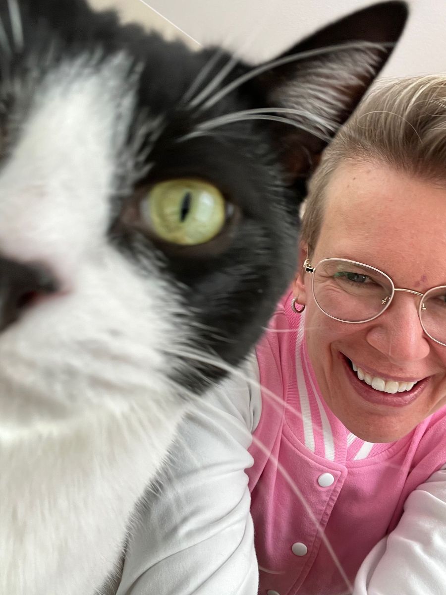 close up of smiling person next to black and white cat