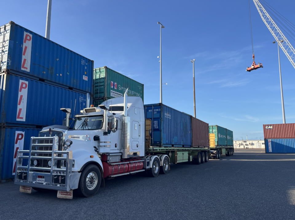 A Semi Truck is Parked in Front of a Pile of Shipping Containers — Harker Haulage In Humpty Doo, NT A Semi Truck is Parked in Front of a Pile of Shipping Containers — Harker Haulage In Humpty Doo, NT