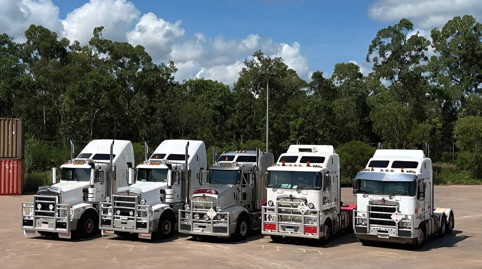 A Row of Semi Trucks Are Parked in a Parking Lot — Harker Haulage In Howard Springs, NT A Row of Semi Trucks Are Parked in a Parking Lot — Harker Haulage In Howard Springs, NT