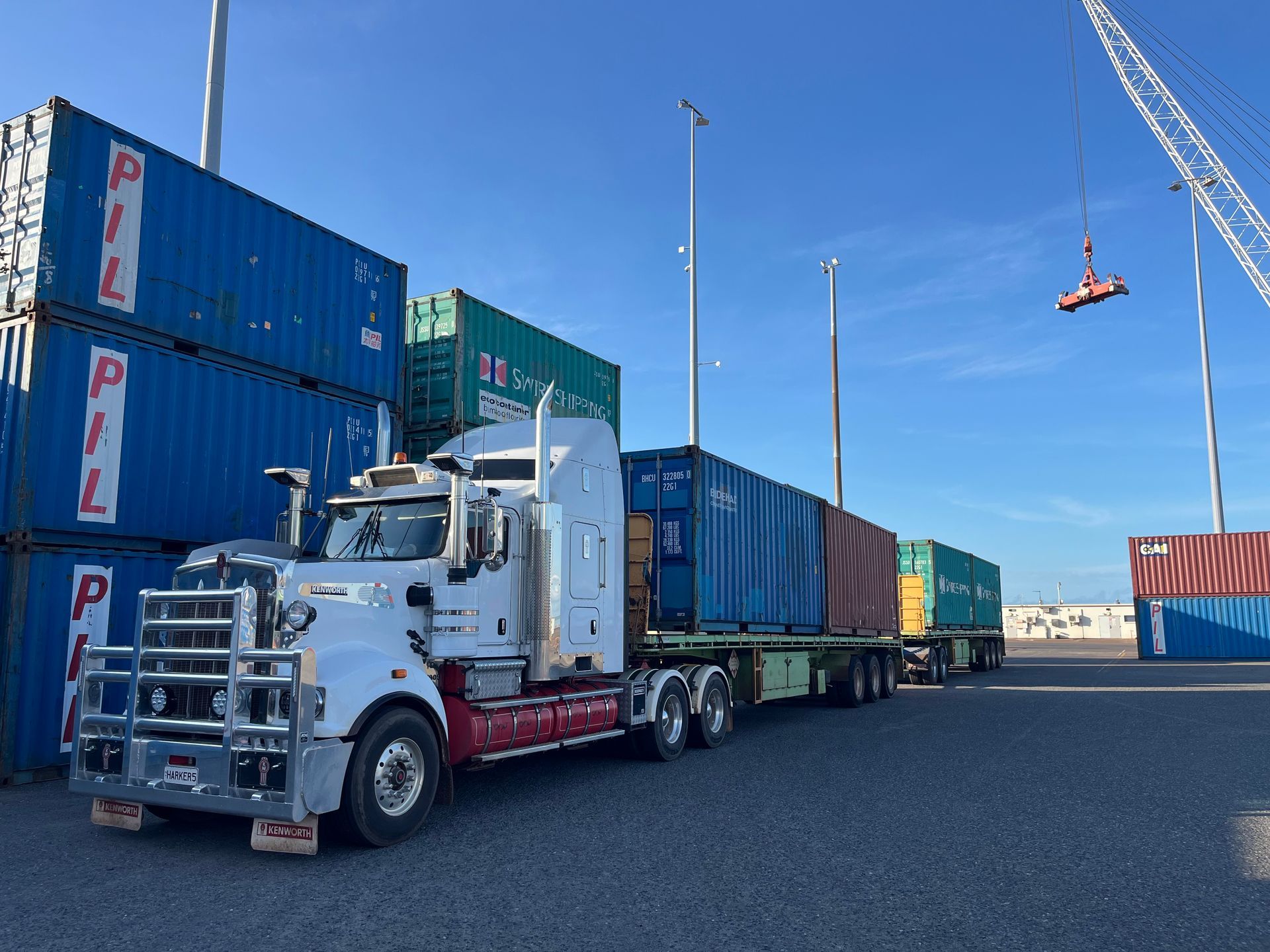Semi-truck loaded with shipping containers at a port, blue sky. — Harker Haulage In East Arm, NT