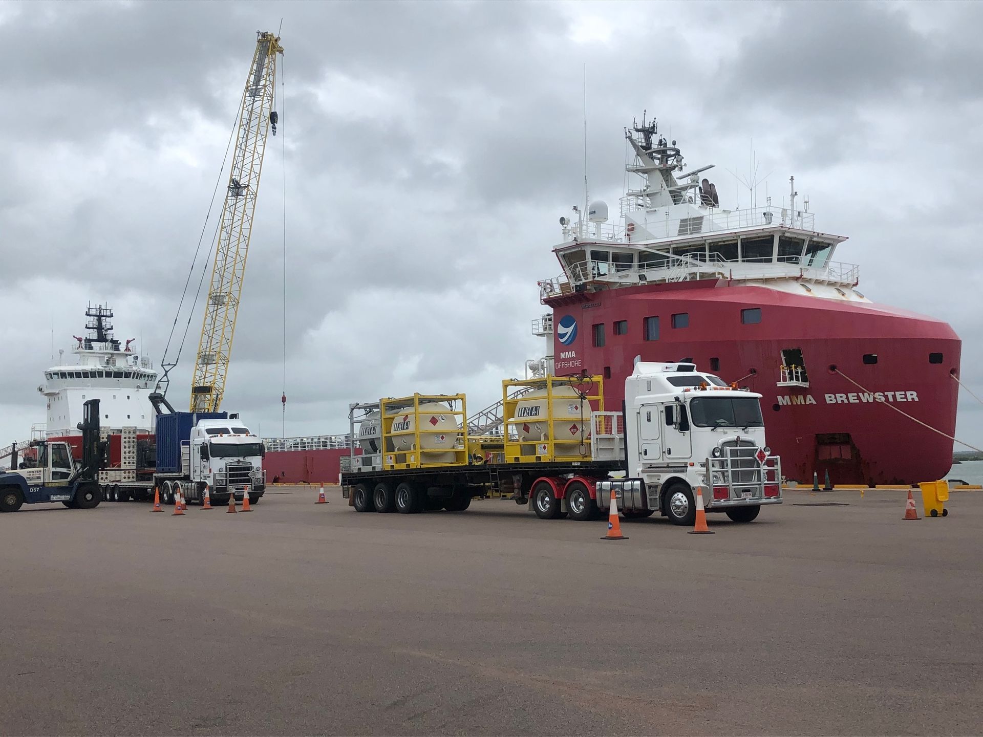 Trucks loading cargo onto a red ship at a dock; a crane is also present. — Harker Haulage In East Arm, NT
