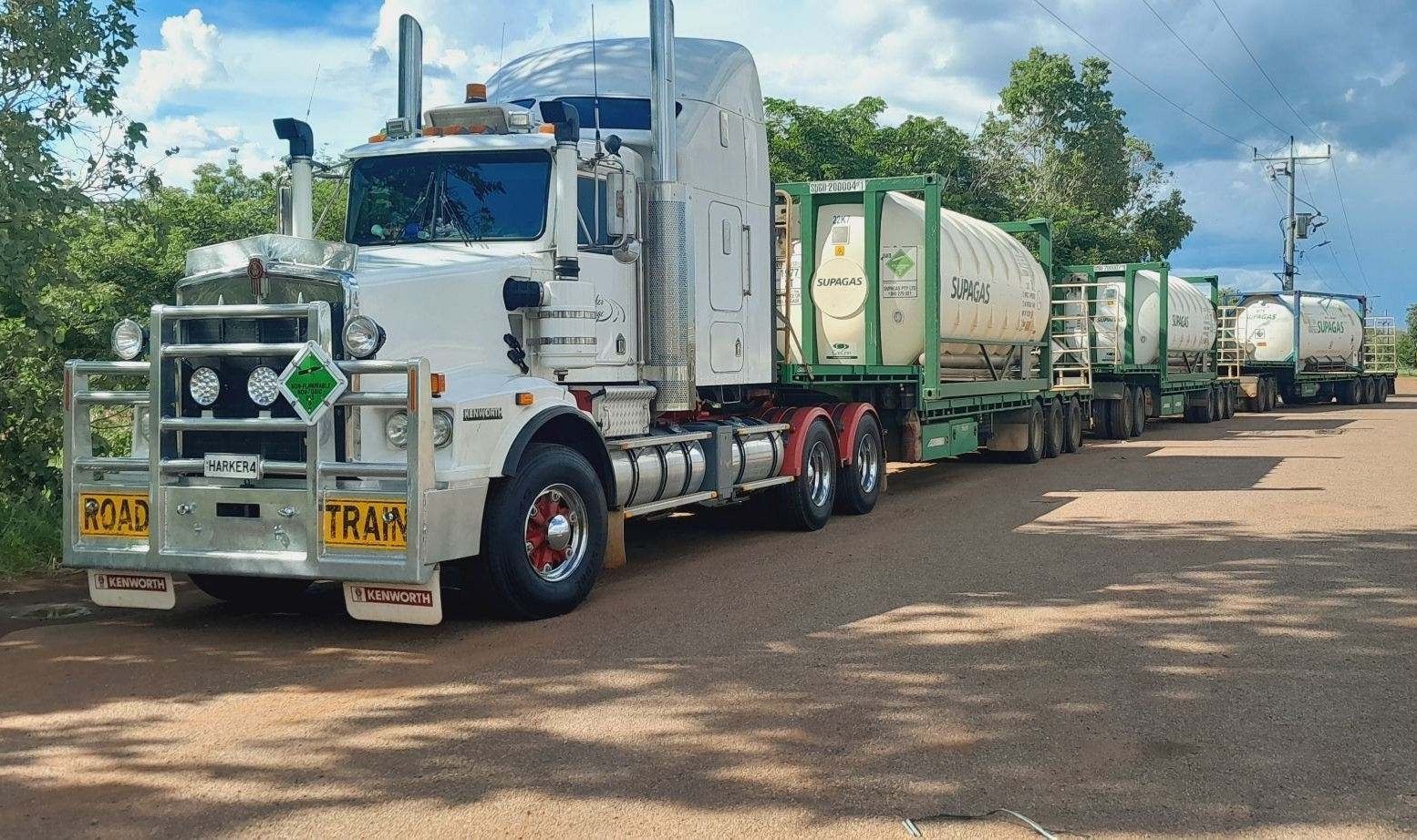 White semi-truck towing several tanker trailers on a gravel road, under a partly cloudy sky. — Harker Haulage In East Arm, NT