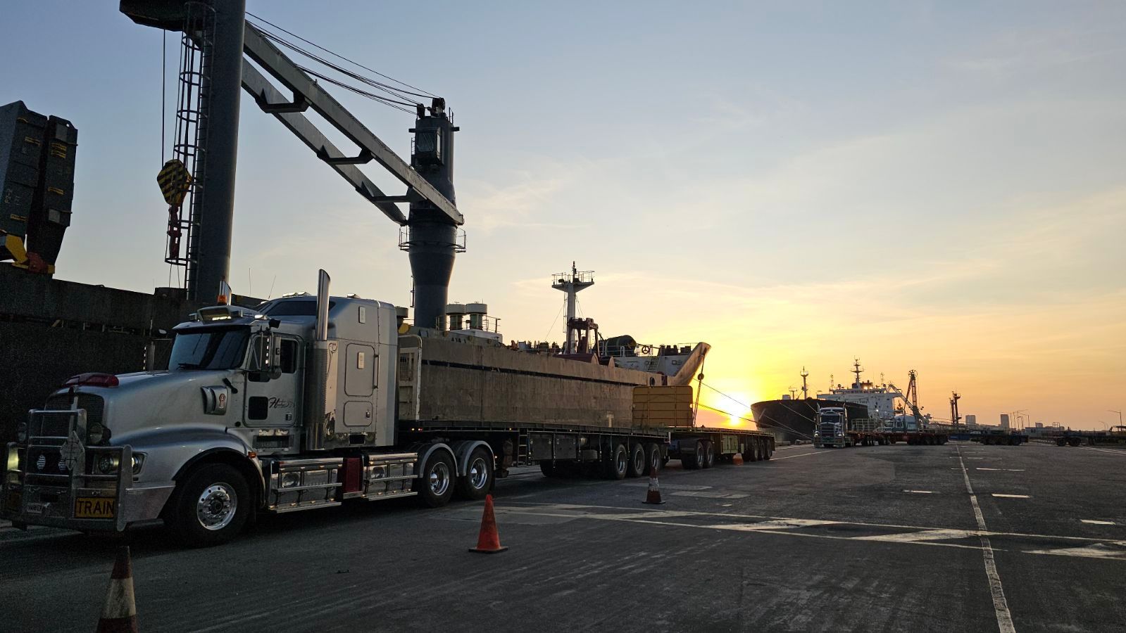 Truck loading at a port, sunset in background. Crane loading truck trailer with cargo. — Harker Haulage In East Arm, NT