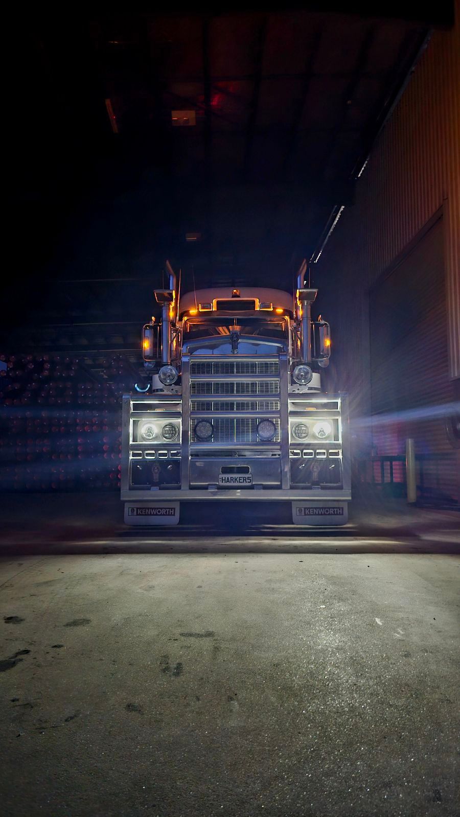 A white semi truck is parked in a puddle of water.