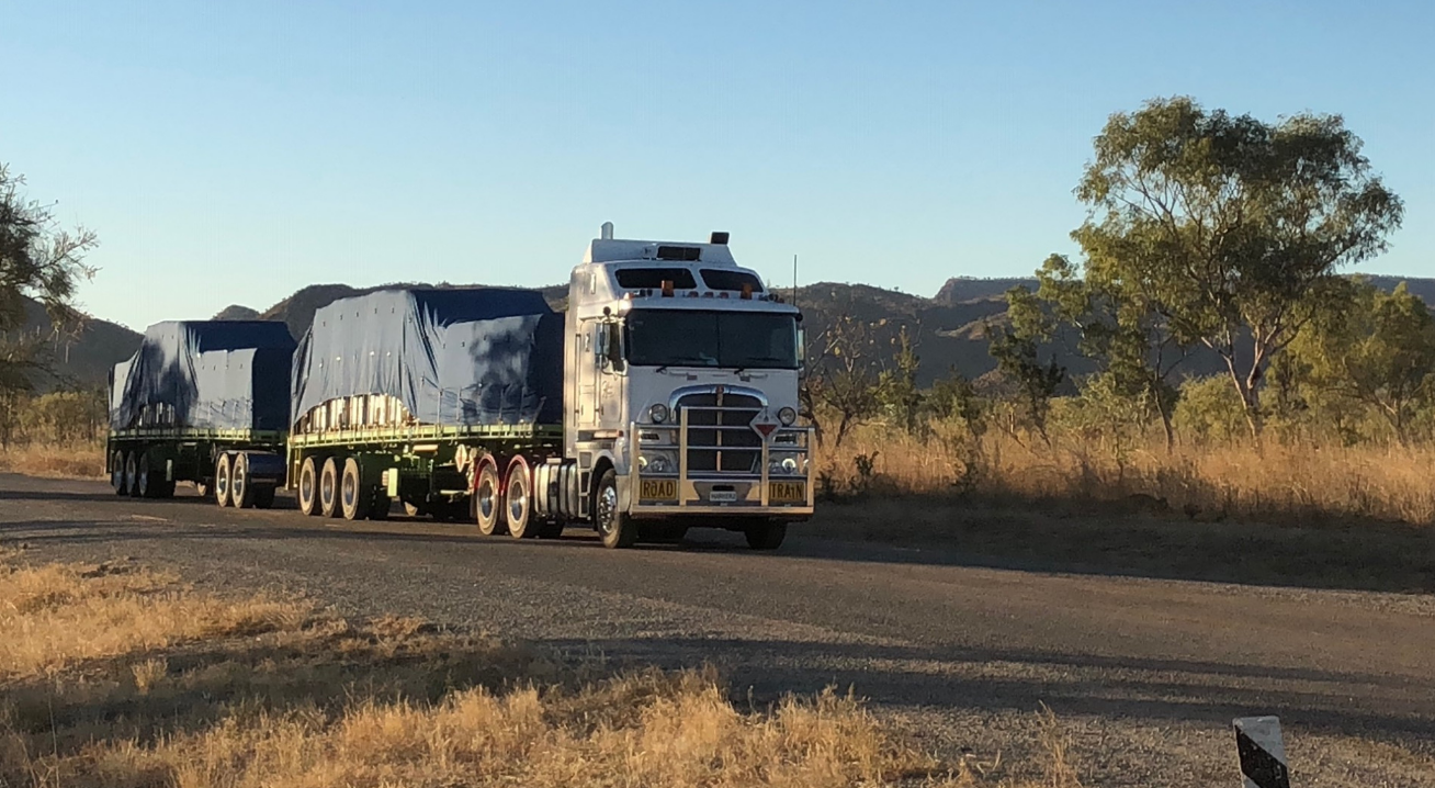 A Large Semi Truck is Driving Down a Dirt Road — Harker Haulage In East Arm, NT