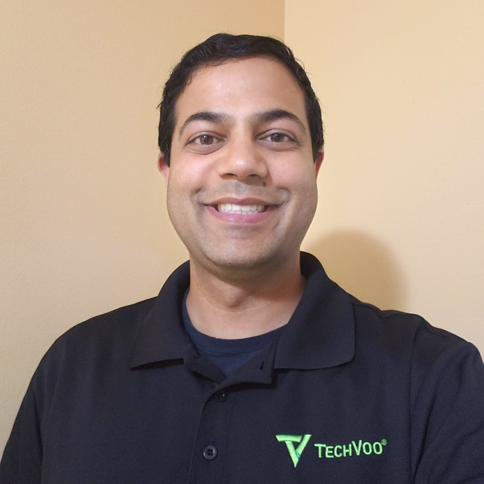 A man wearing a black techvoo polo shirt smiles for the camera