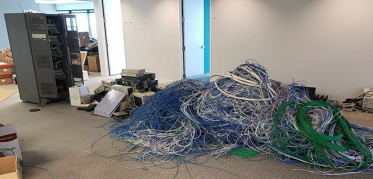 A room with debris. A large pile of blue, white and green cables, and damaged metal structures.