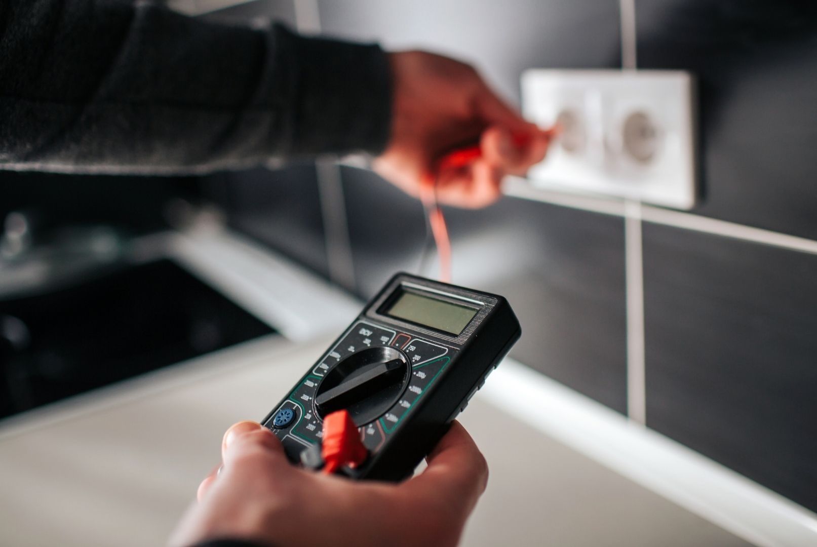 A person is using a multimeter to test an electrical outlet.