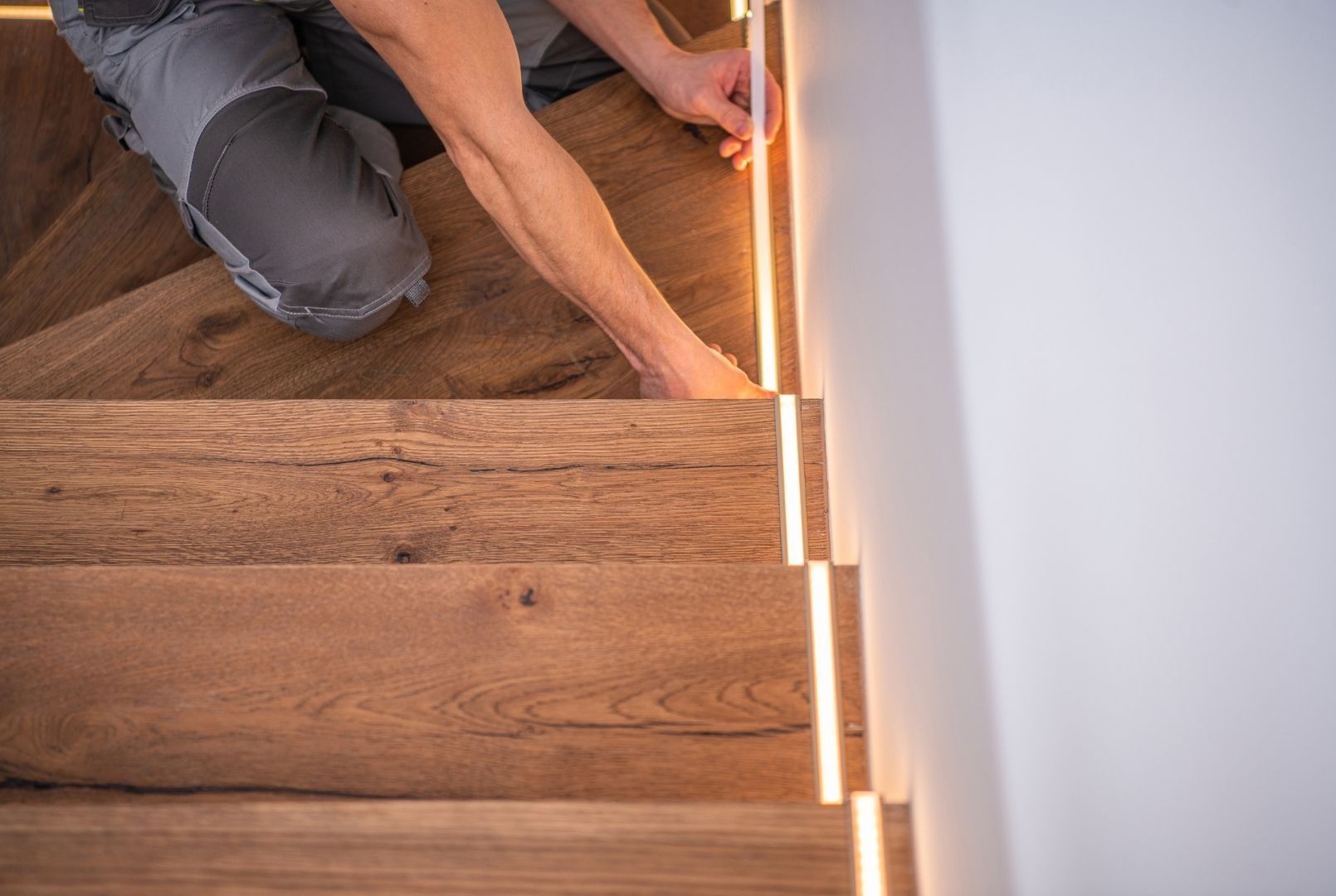 A man is installing a wooden floor on a set of stairs.