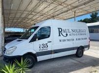 Un'auto bianca è parcheggiata su un vialetto di mattoni davanti a una recinzione.