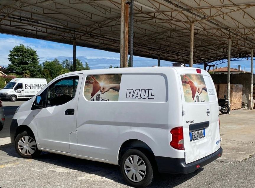 Un'auto verde è parcheggiata su un vialetto di mattoni davanti a una recinzione.