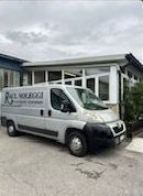 Una Ford C-Max bianca è parcheggiata su un vialetto in mattoni di fronte a una casa.