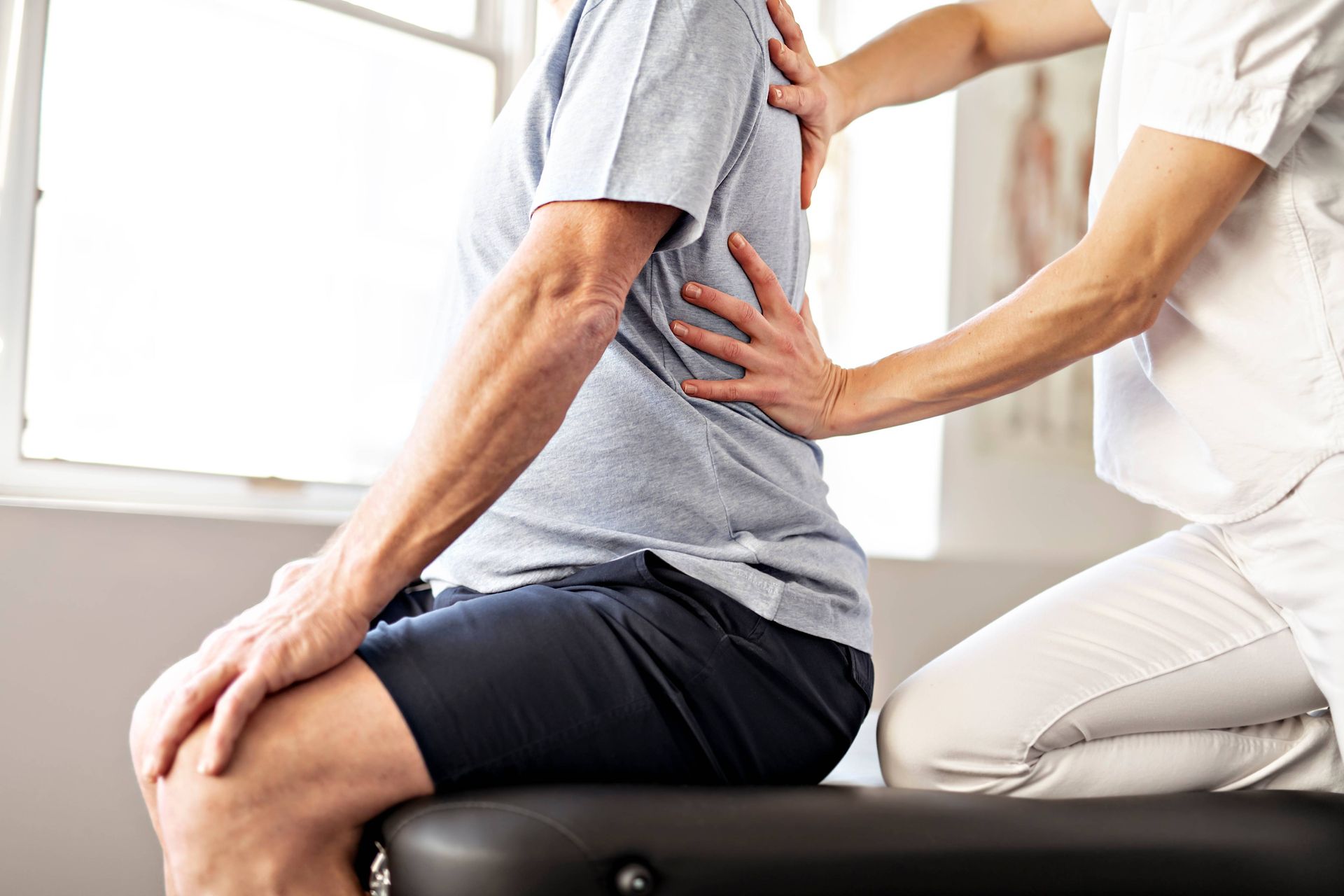 A man is sitting on a table getting a back massage from a nurse.