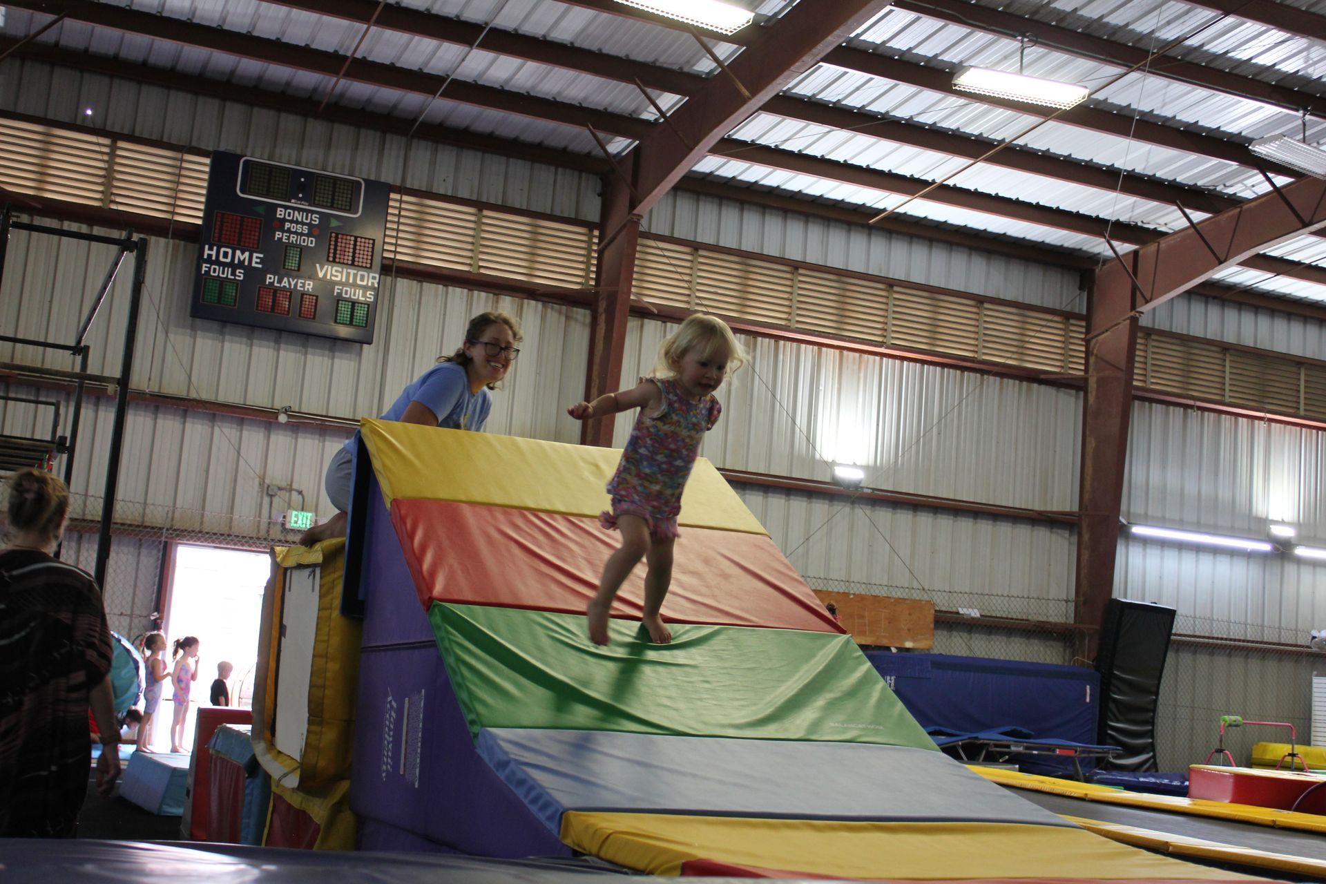 A young boy in a white shirt is flexing his muscles.