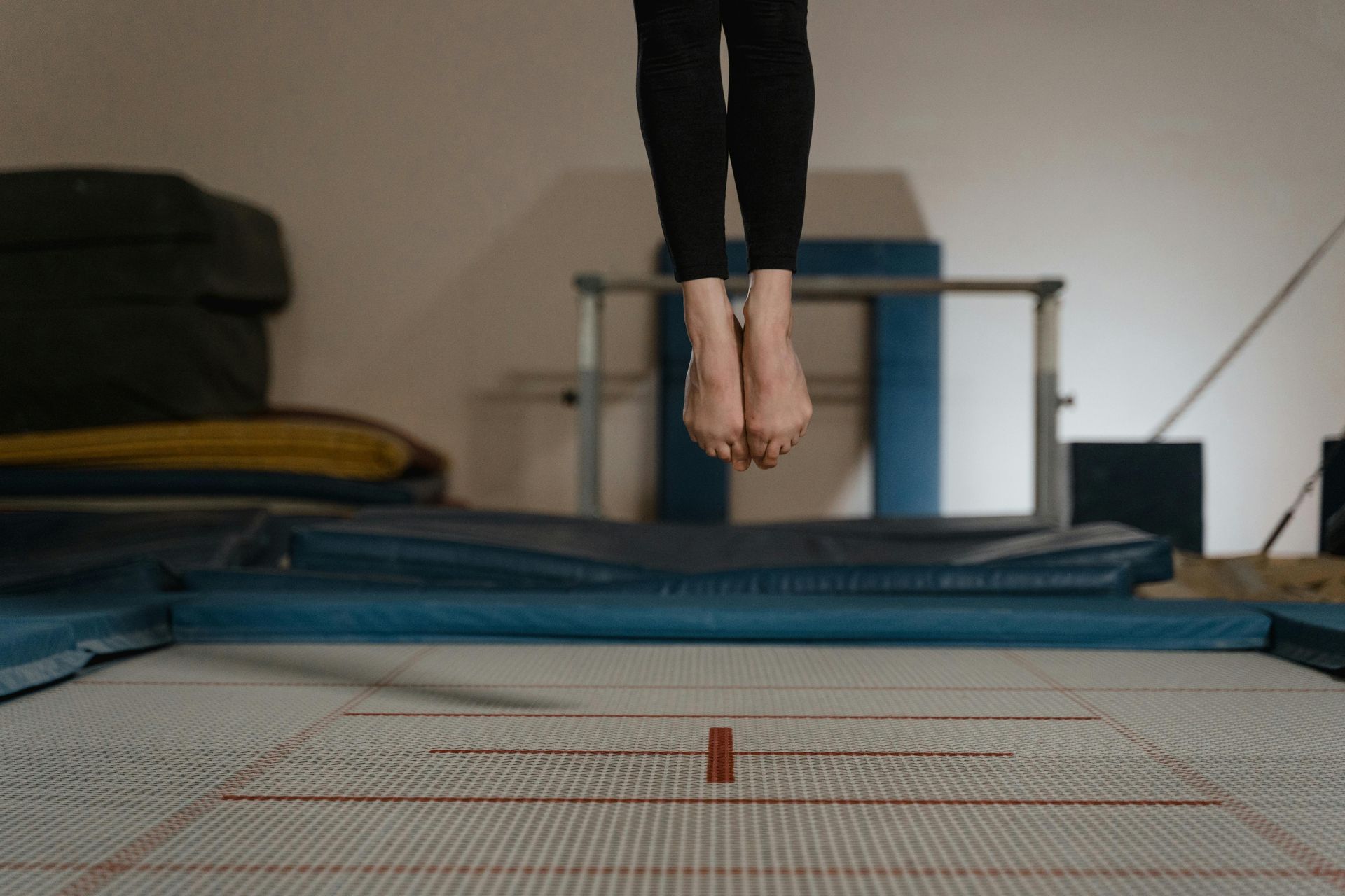 A gymnast is sitting on a balance beam covered in chalk.